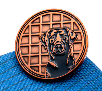Antique copper lapel pin featuring a black Labrador retriever portrait against a waffle pattern background.