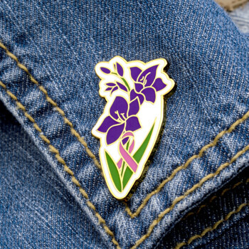 Enamel lapel pin featuring purple gladiolus flowers and a pink awareness ribbon on a white background with gold plating.